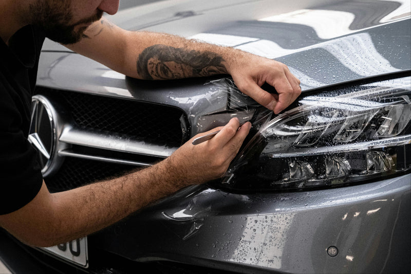 Person applying car wrap to a vehicle's headlight and front area at element care melbourne
