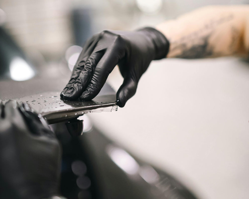 Person working on a car with a focus on hands wearing gloves at element care melbourne