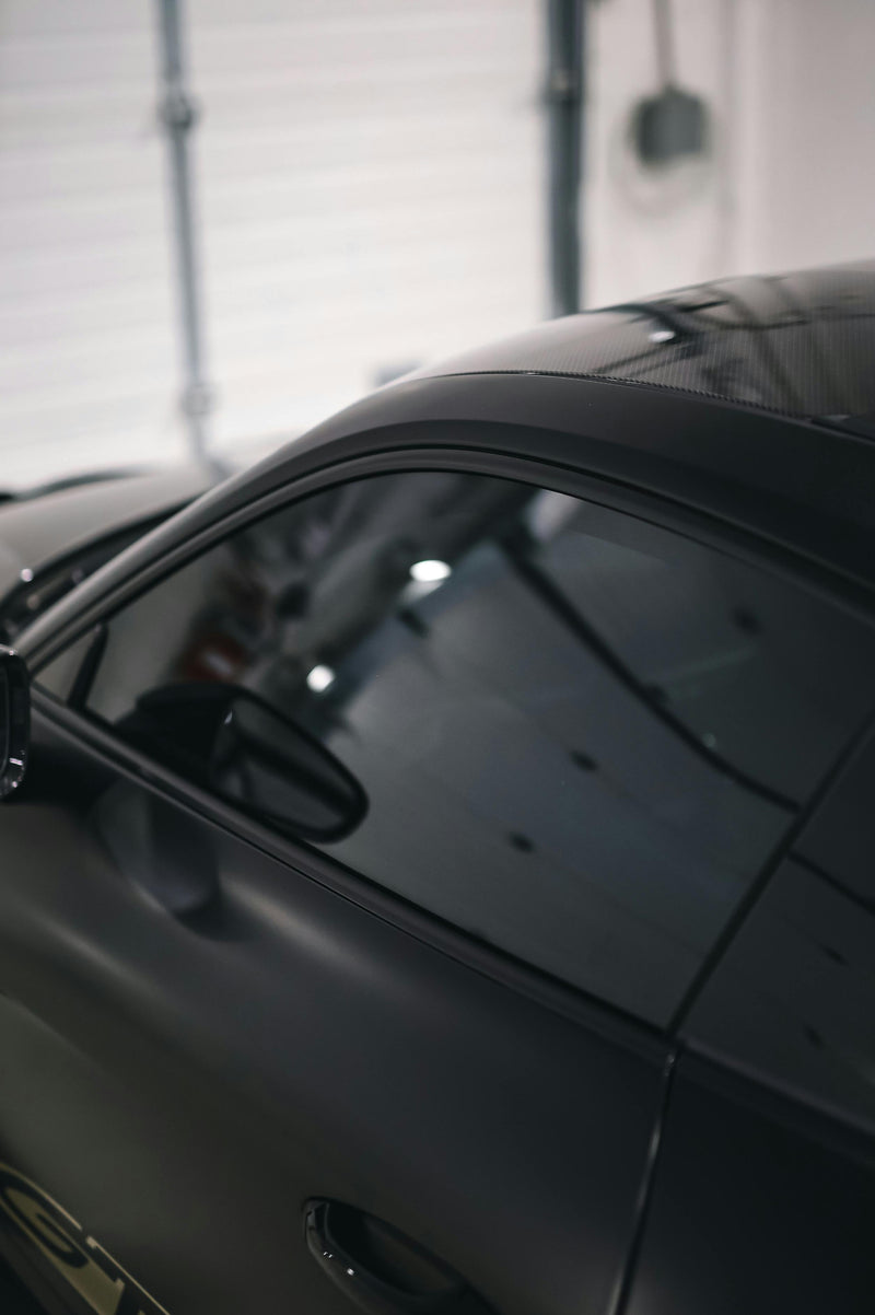 Close-up of a black car's side mirror and window highlighting window tint in a garage setting at element care melbourne